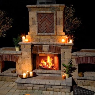 A brick fireplace with candles lit in it.