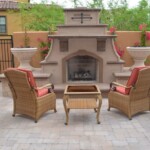 A patio with chairs and tables around an outdoor fireplace.
