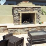 A stone fireplace sitting in the middle of an outdoor patio.