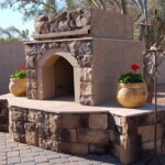 A stone fireplace with flowers in the middle of it.