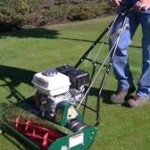 A man is using an electric mower to cut the grass.