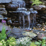 A waterfall in the middle of some rocks and plants.
