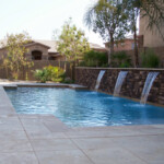 A pool with water jets and a stone wall.