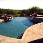 A pool with a waterfall and a stone wall.