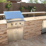 A grill and sink in an outdoor kitchen.