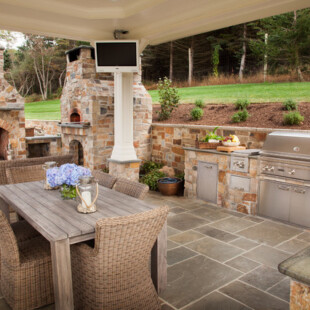 A patio with an outdoor kitchen and dining table.