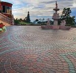 A large brick patio with a fountain in the middle.