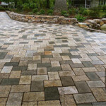 A brick walkway with a stone wall and a rock garden.