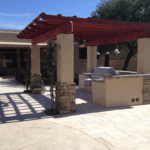 A patio with an outdoor grill and a pergola.