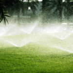 A lawn with sprinklers spraying water on it.