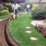 A man is working on the side of a garden.