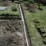 A view of the ground from above shows a pipe and some grass.